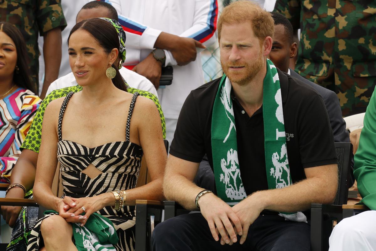 Meghan Markle estaria relutante em dar o divórcio ao príncipe Harry 44 Foto colorida de mulher com vestido estampado. Ela está ao lado de homem ruivo com faixa no pescoço - Metrópoles